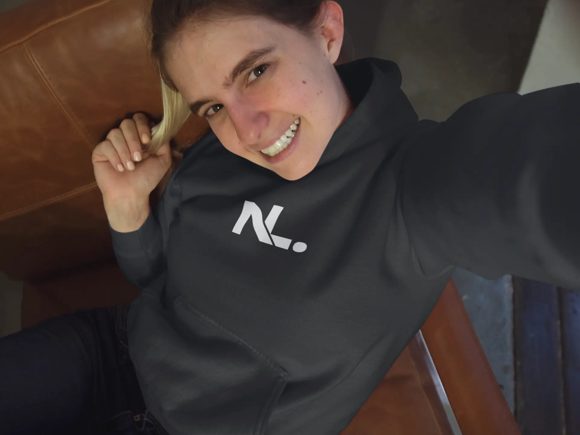 Young woman smiling in hoodie selfie.